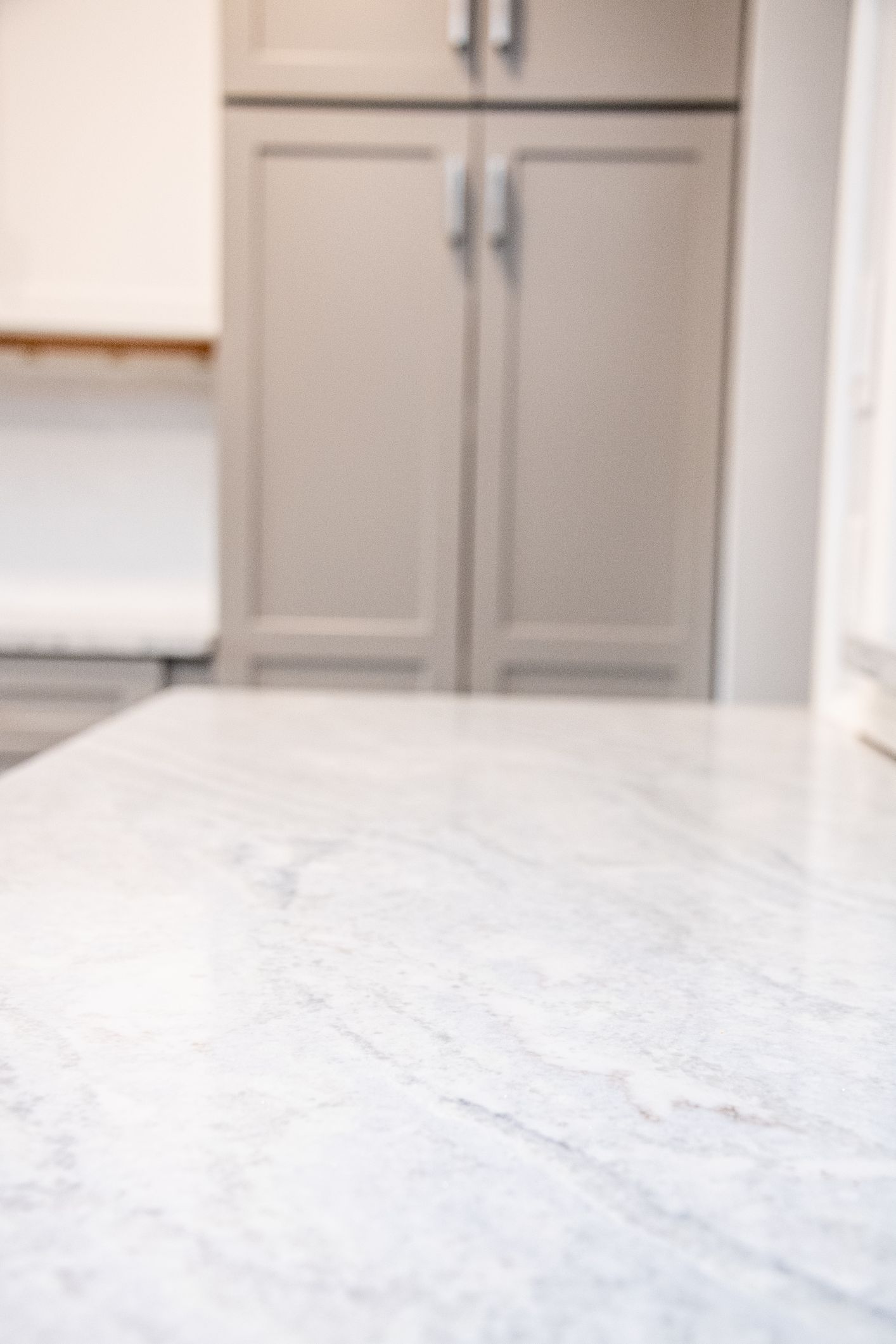 Kitchen counter with light gray marble surface and beige cabinets in the background