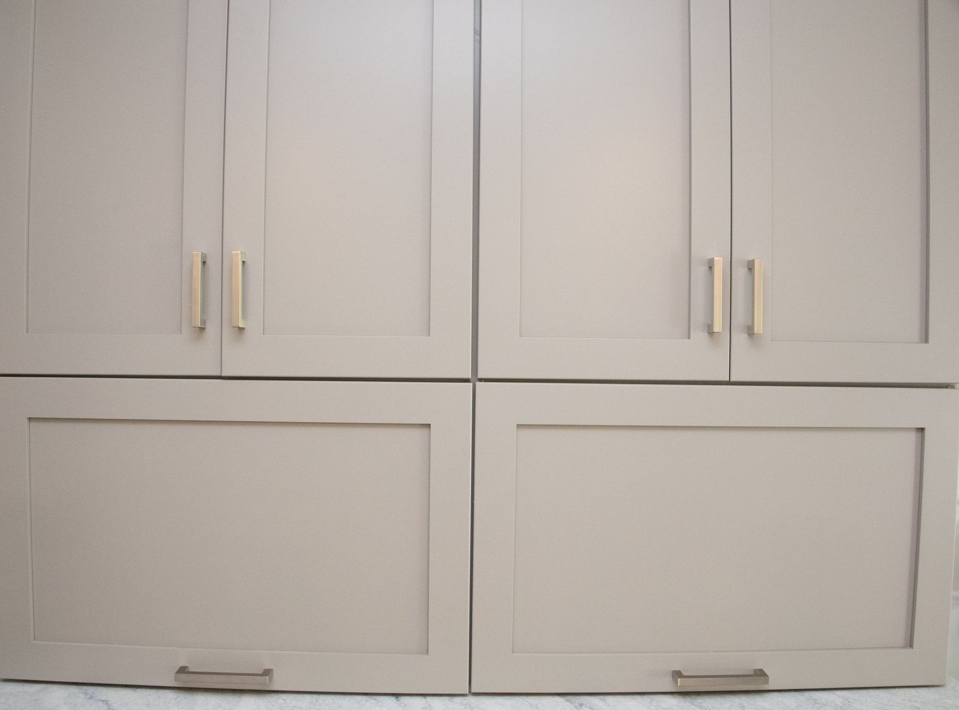 White built-in cabinets with gold handles and lower drawers against a light wall.