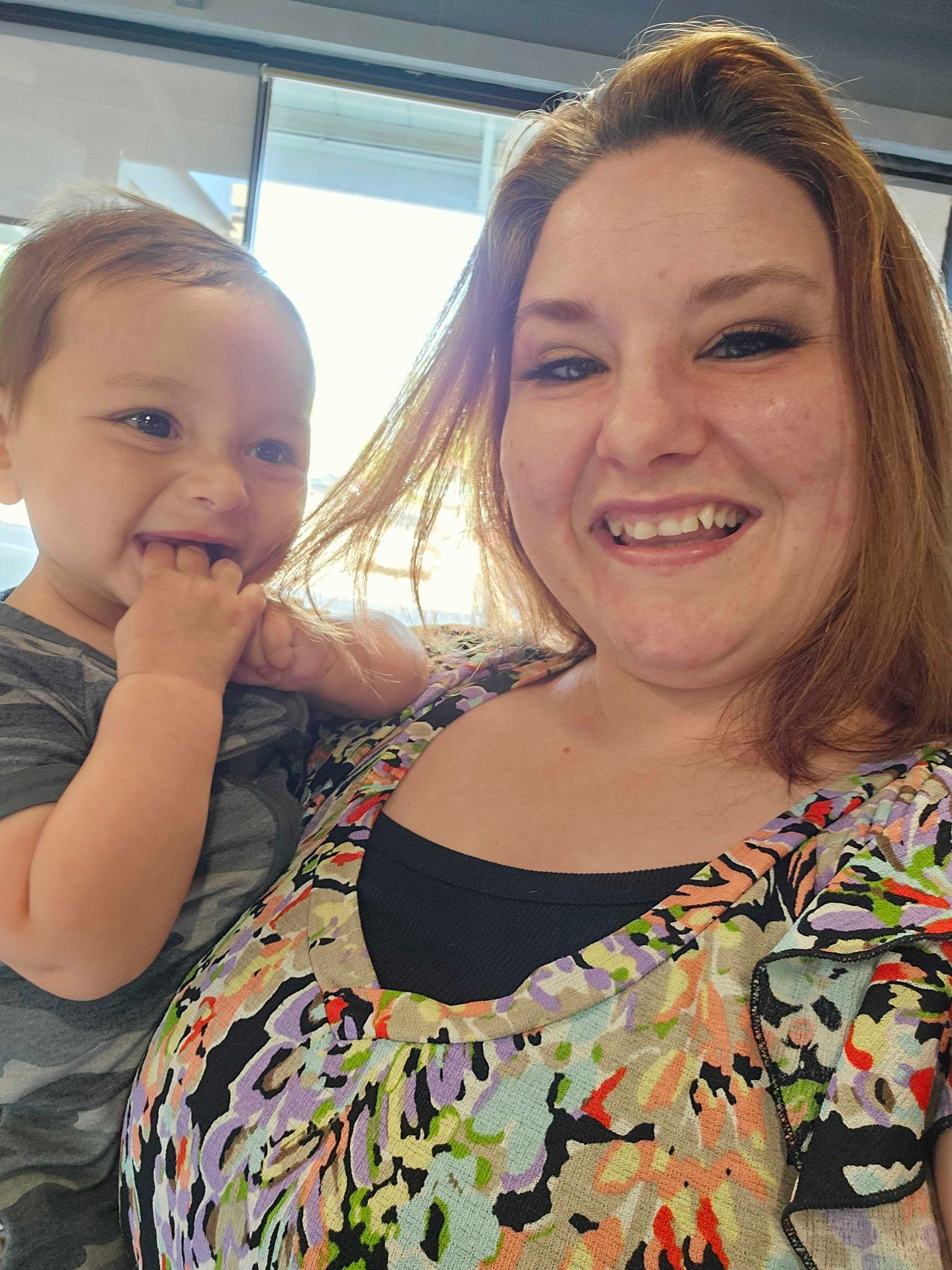 Adult smiling with a toddler indoors near a bright window