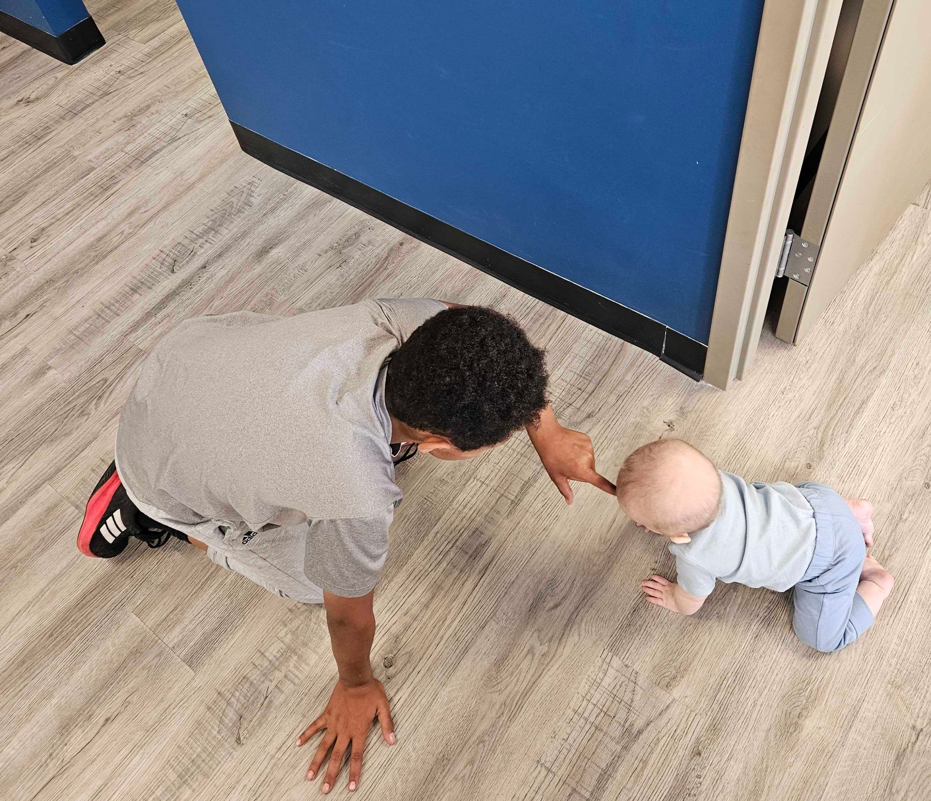 Adult hands gently holding a baby’s hand in a soft, warm close-up.
