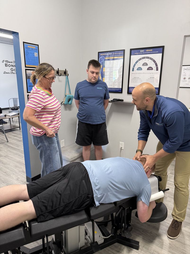Doctor examining a child’s back while a parent stands nearby in a bright clinic room