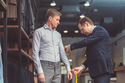 A man is being measured by a tailor in a tailor shop.