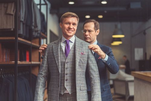 A man is trying on a suit in a tailor shop.