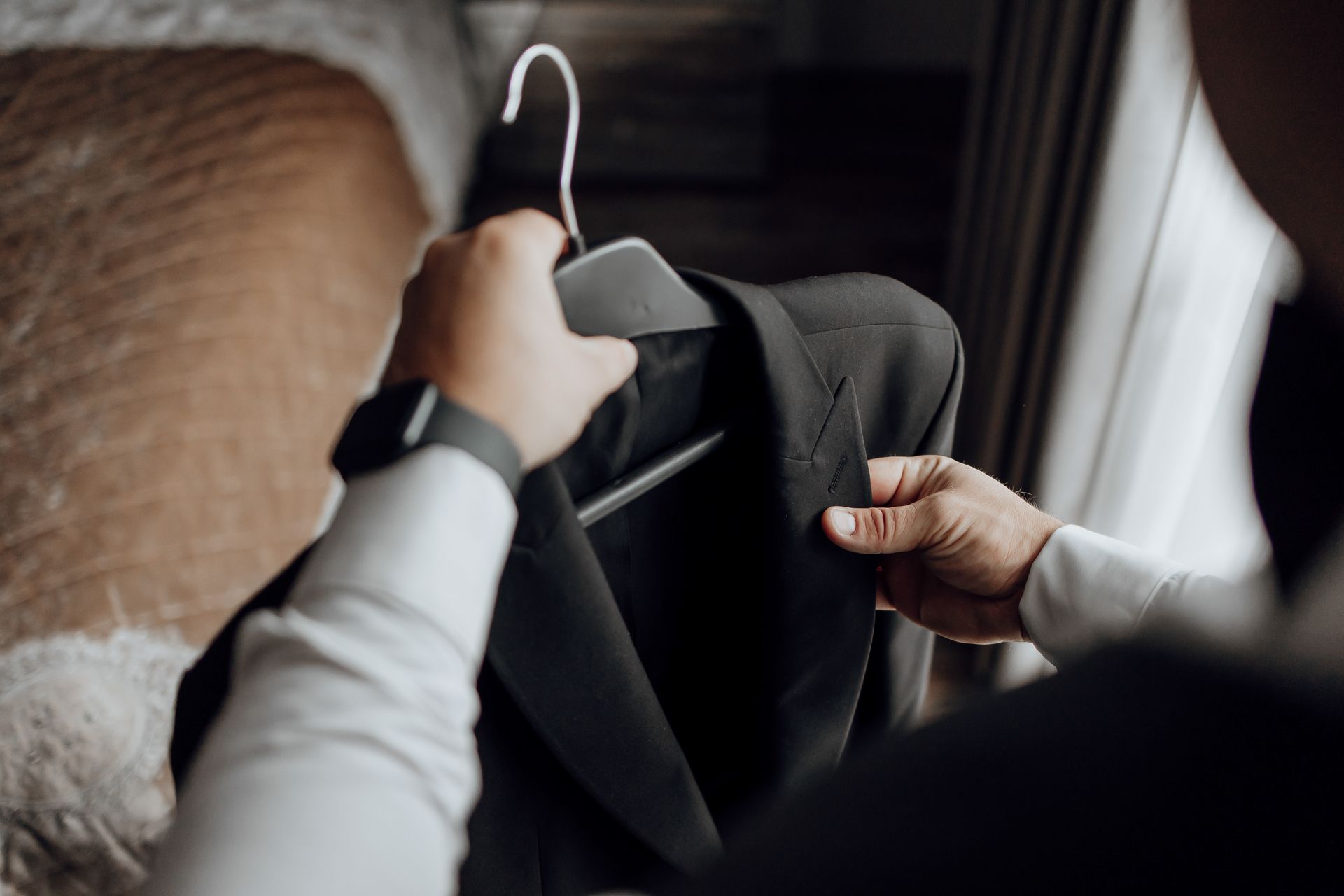 A man is holding a suit jacket on a hanger.