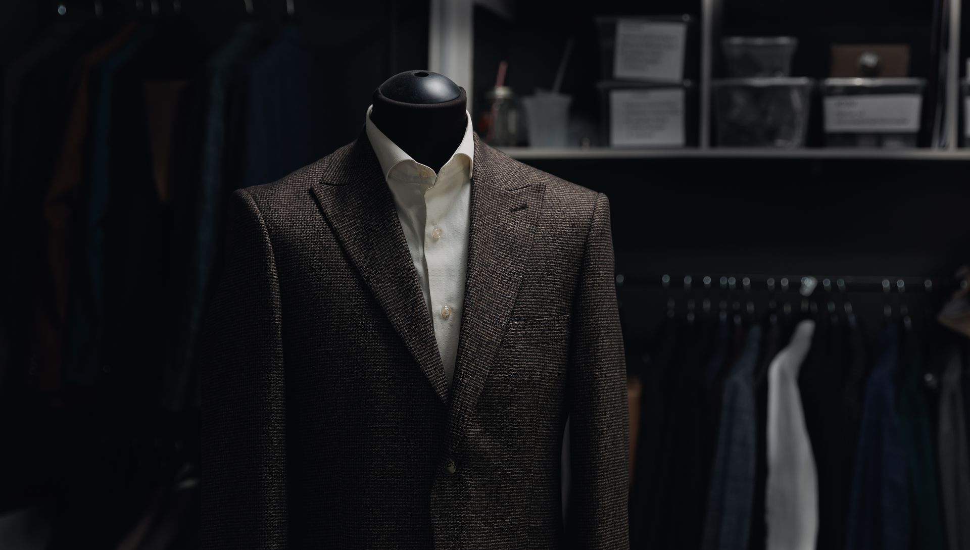 A suit is on a mannequin in a closet.