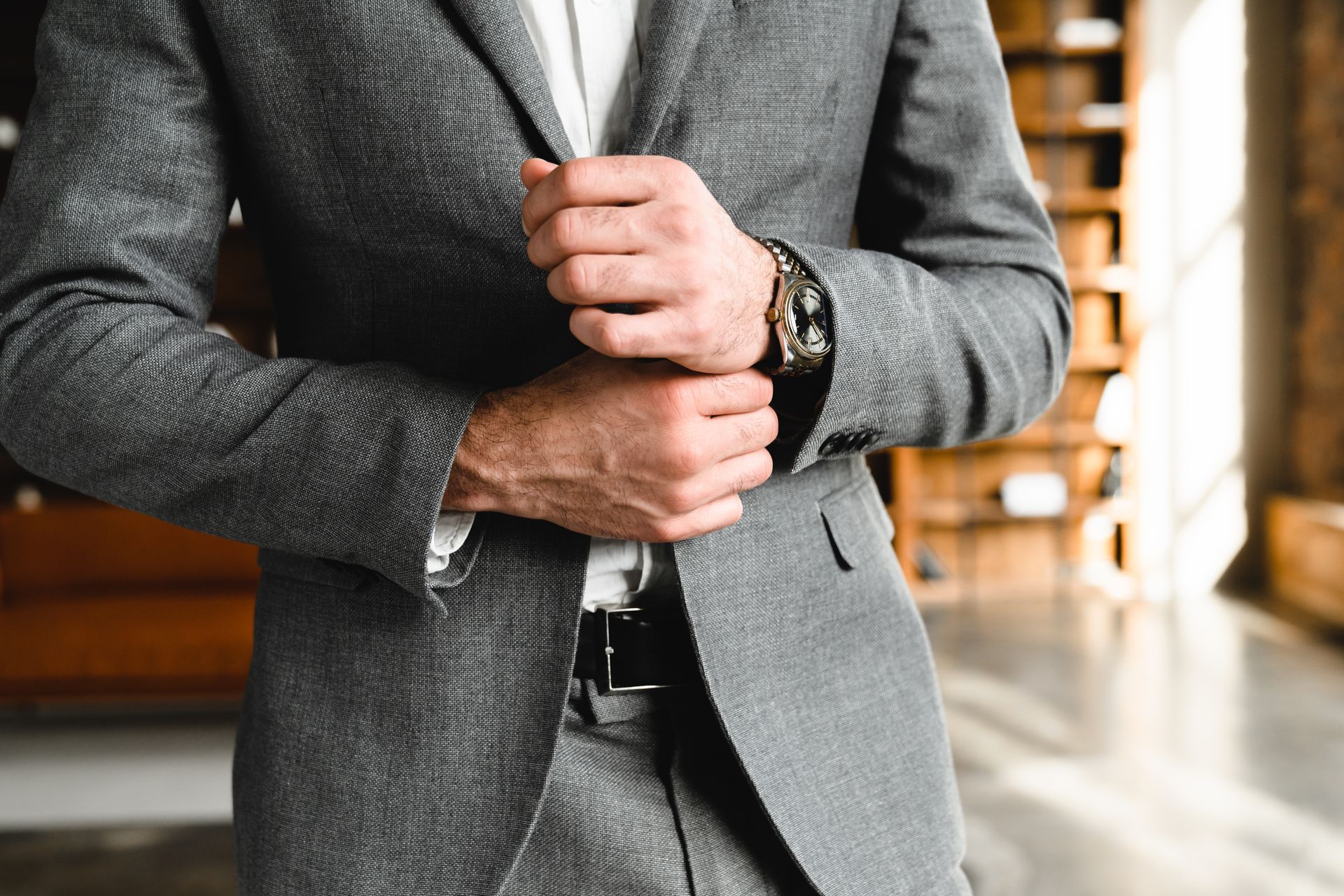A man in a suit is adjusting his jacket.