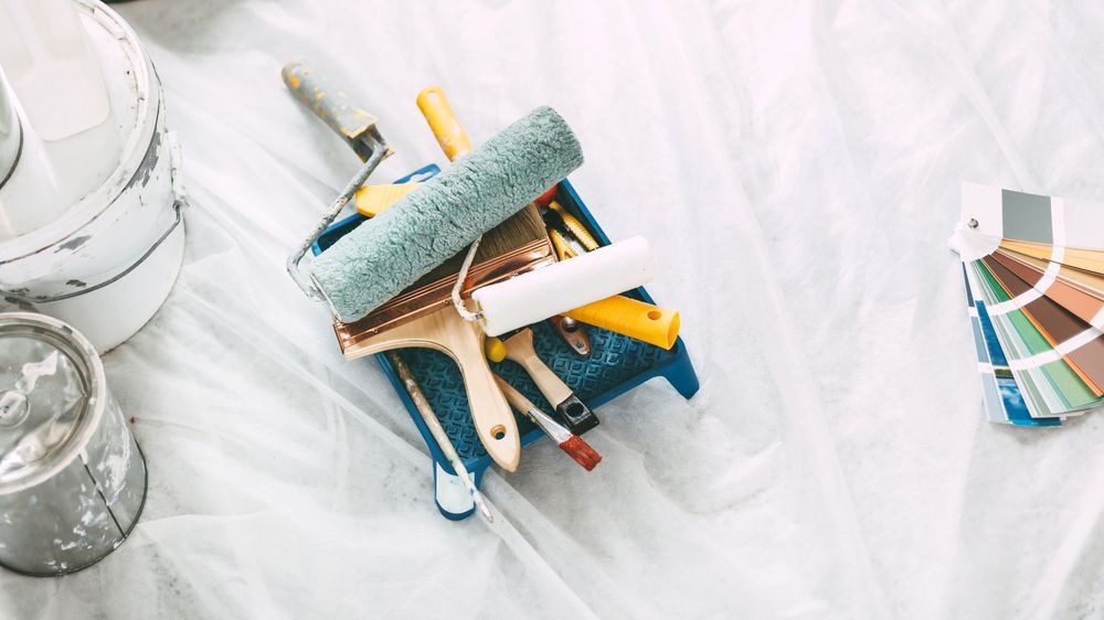 a tray with paint rollers and brushes on it
