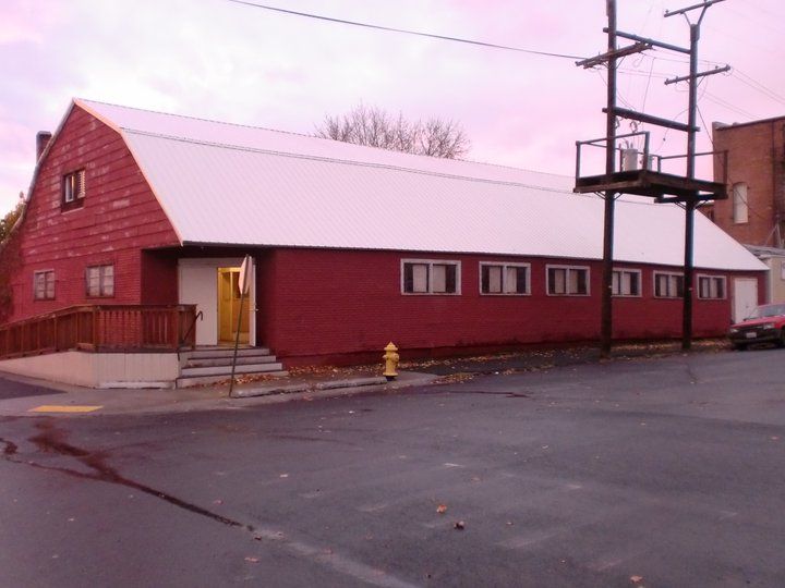 Red building with a white roof; yellow door, fire hydrant, and utility pole.
