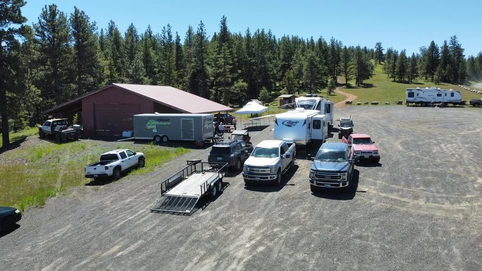 Several trucks and campers parked near a red building in a gravel lot