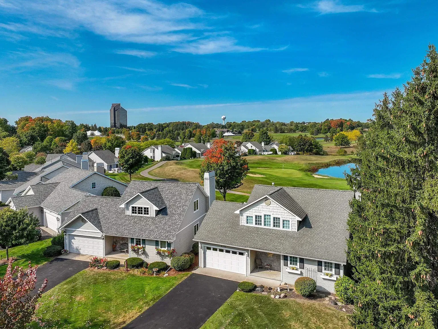 Suburban homes with gray roofs overlooking a green landscape and blue sky