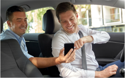 Um homem está sentado no banco de trás de um carro olhando para o telefone.