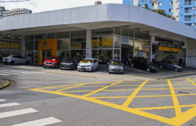 Uma fileira de carros está estacionada em frente a uma concessionária de automóveis