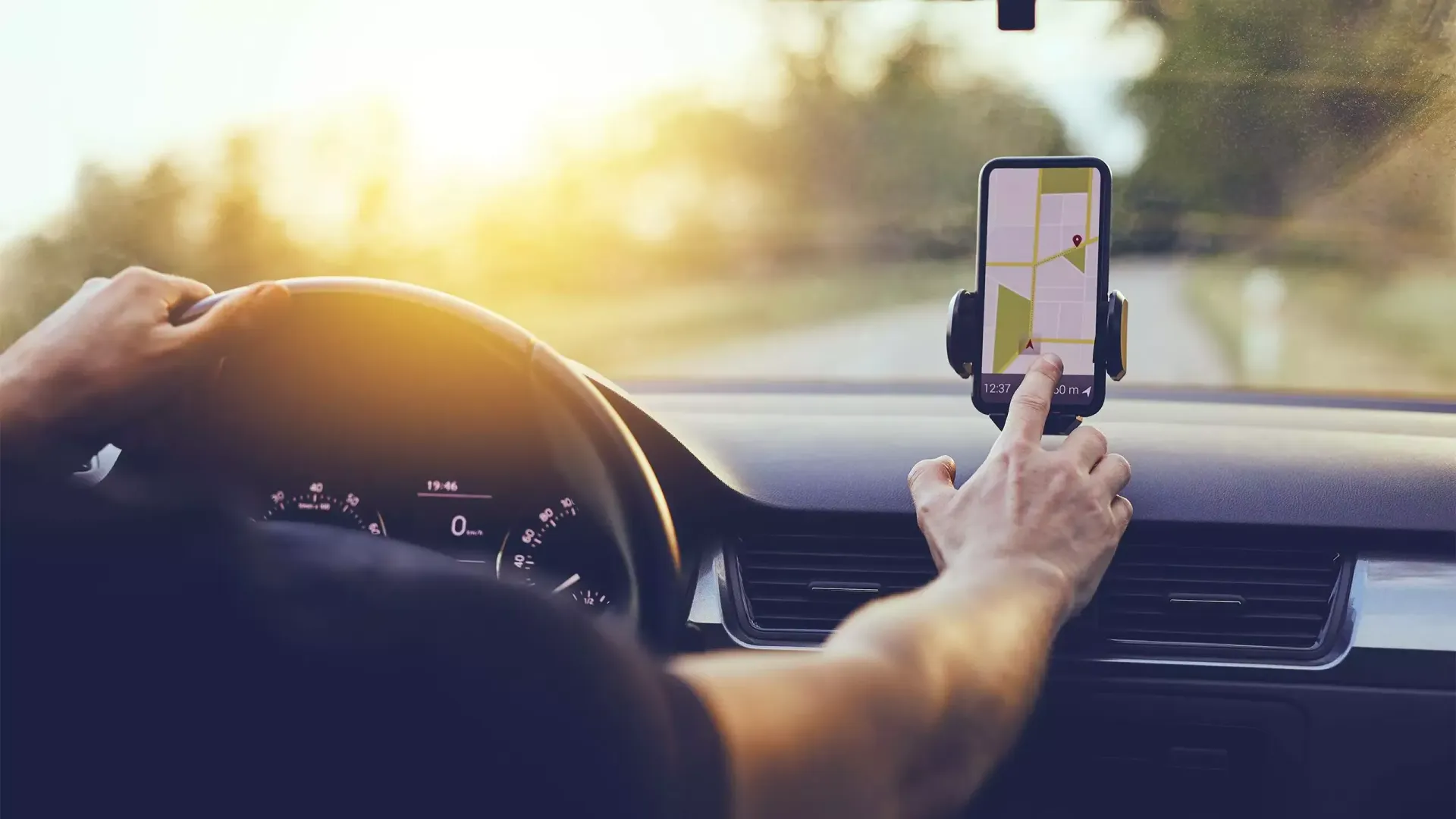 Um homem está dirigindo um carro enquanto mexe no gps.