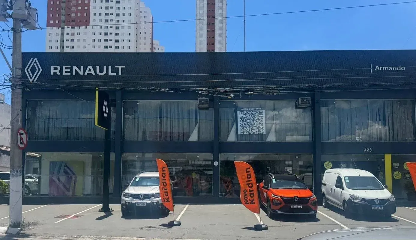 Uma concessionária de carros Renault com carros estacionados em frente a ela.