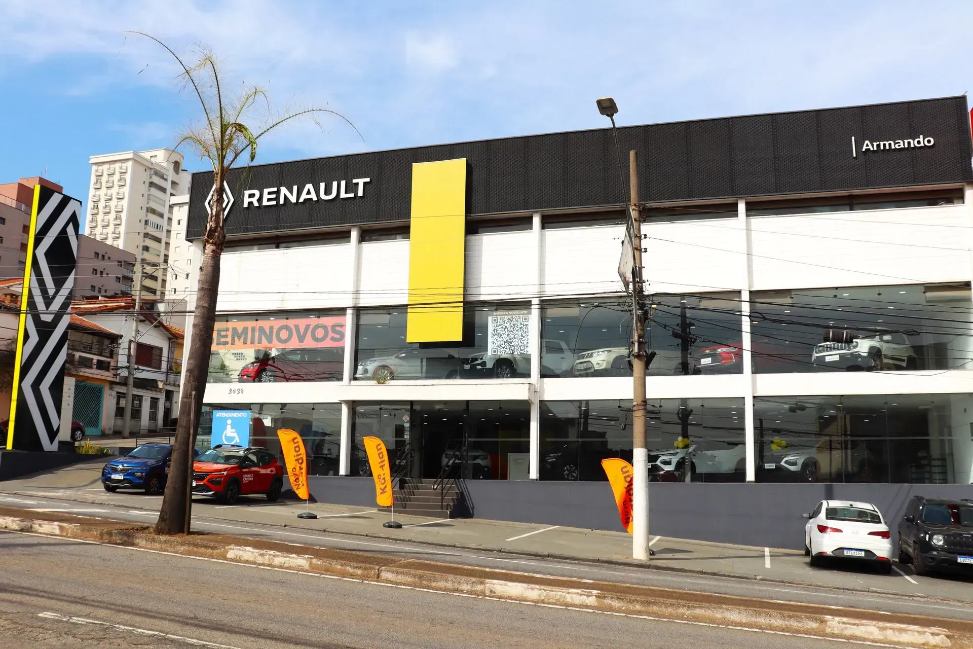 Uma concessionária de carros Renault com carros estacionados em frente a ela.