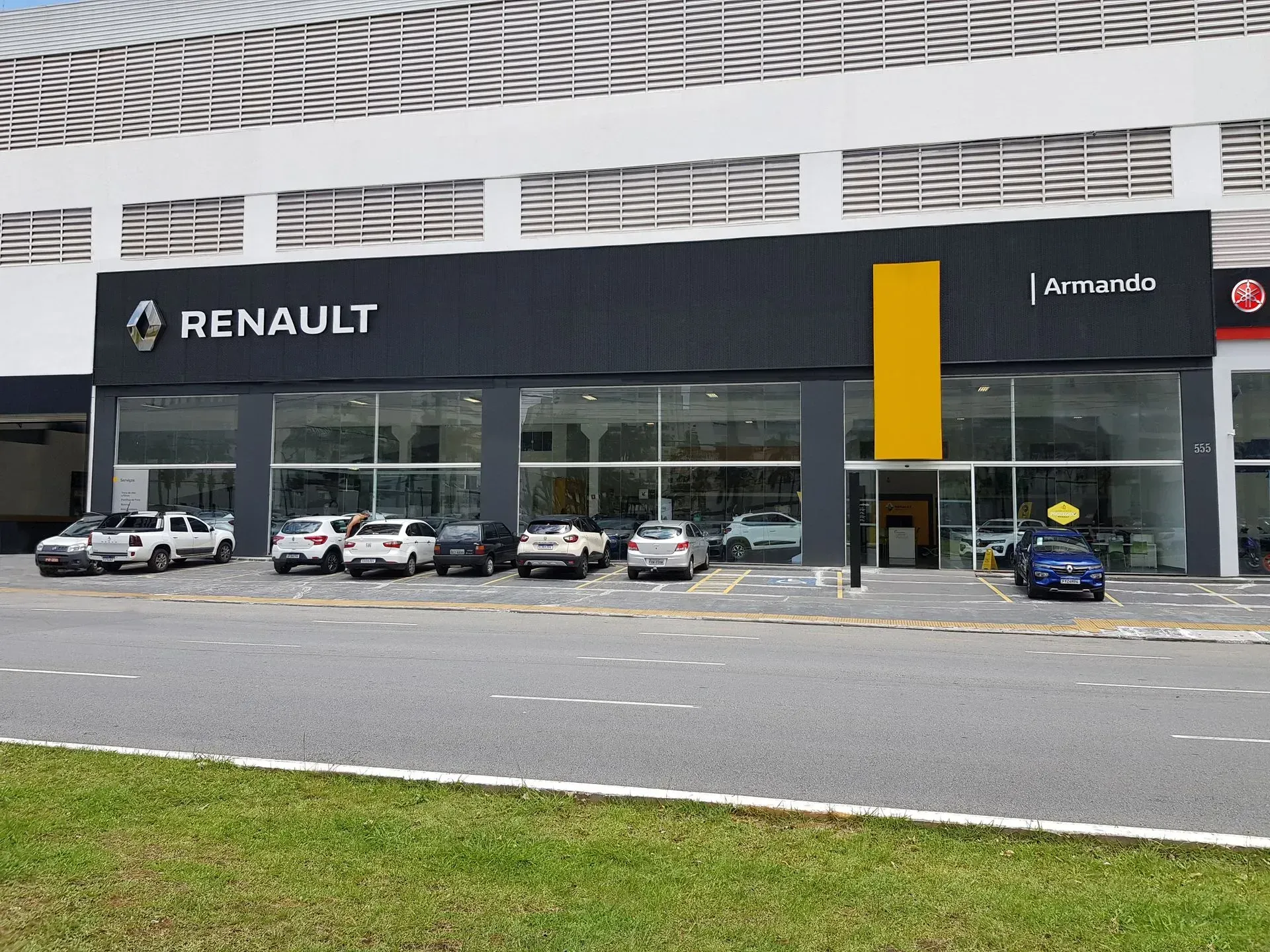Uma fileira de carros está estacionada em frente a uma concessionária de carros Renault.