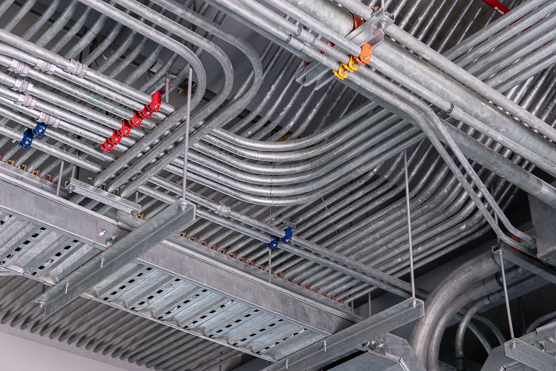 A bunch of metal pipes are hanging from the ceiling of a building.