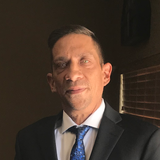 A man in a suit and tie is standing in front of a window, one of Treasure Valley Ads customers who provided a testimonial.