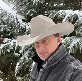 A man wearing a cowboy hat is standing in front of snow covered trees, one of Treasure Valley Ads customers who provided a testimonial. 