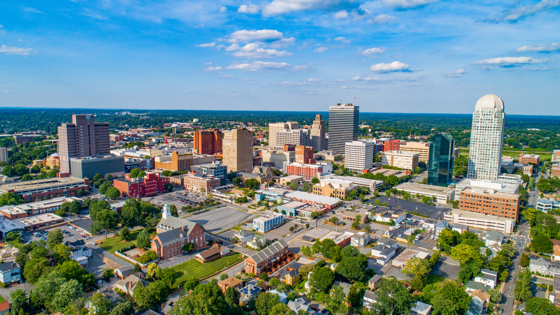Aerial view of a downtown skyline with tall buildings and a large white human-shaped sculpture