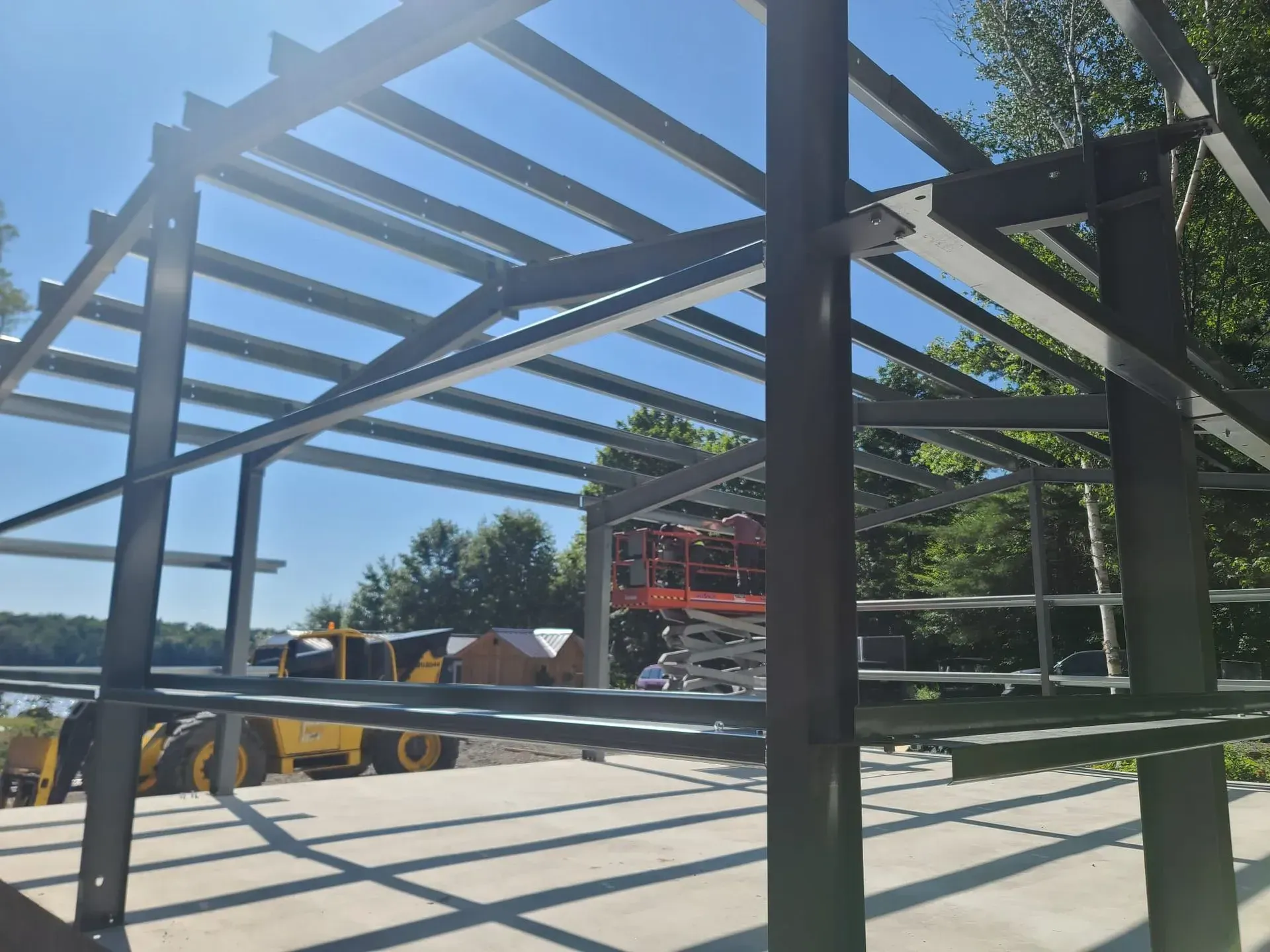 Steel framework of a building under construction with a crane and equipment on a sunny day