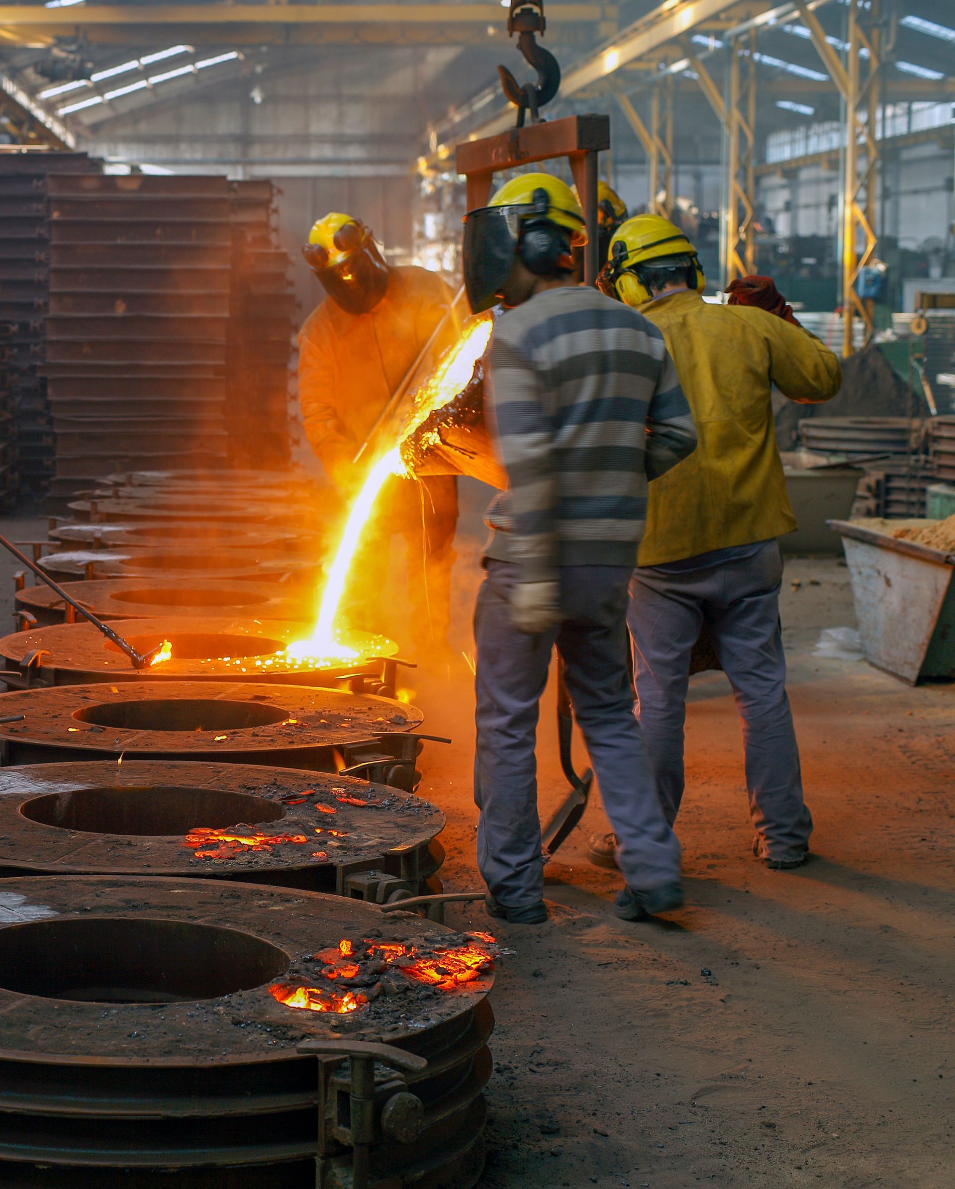 Workers pouring glowing molten metal in an industrial foundry