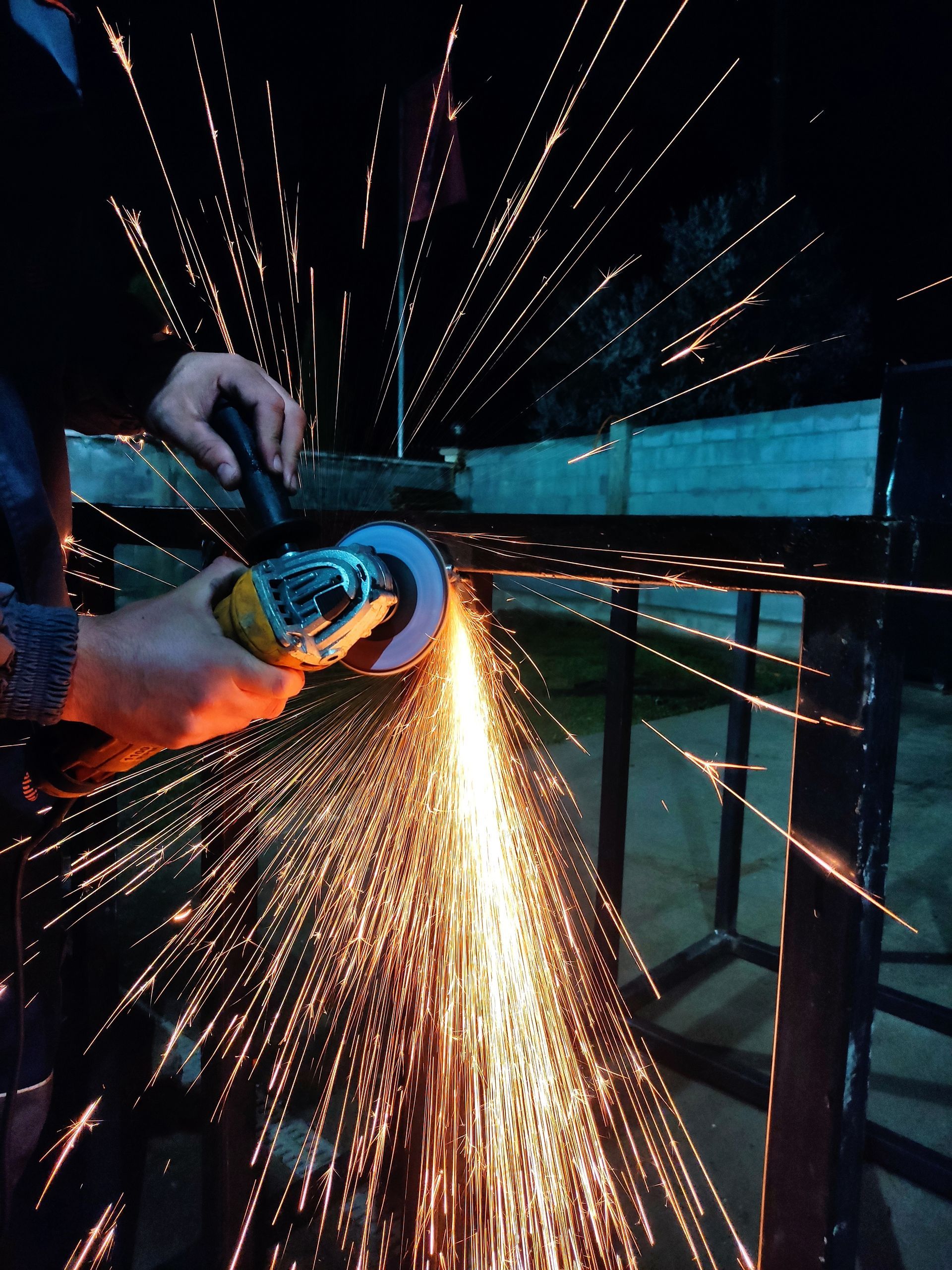 Person using a grinder sparks flying in a dark workshop
