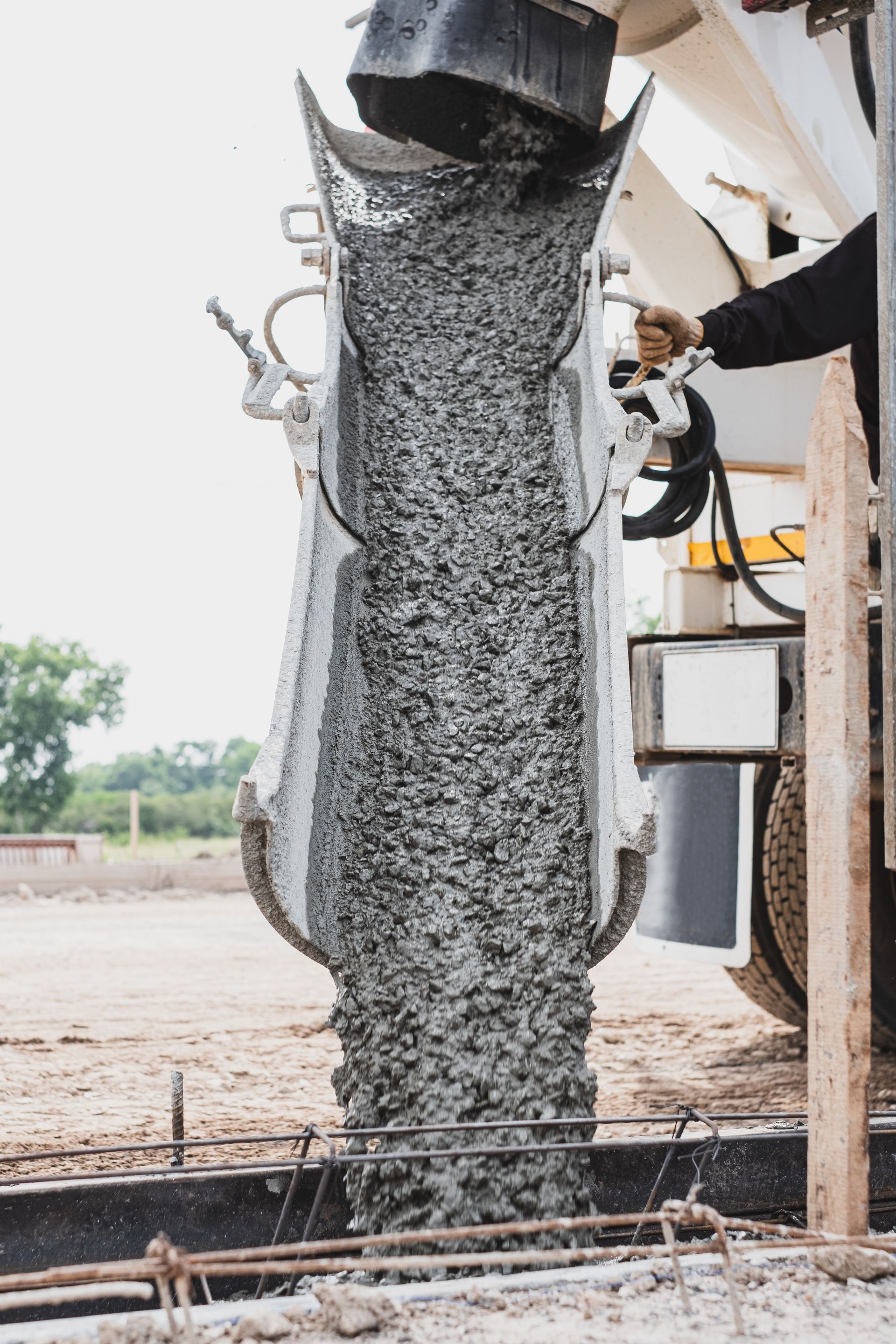 Wet concrete pouring from a chute into a construction site form.
