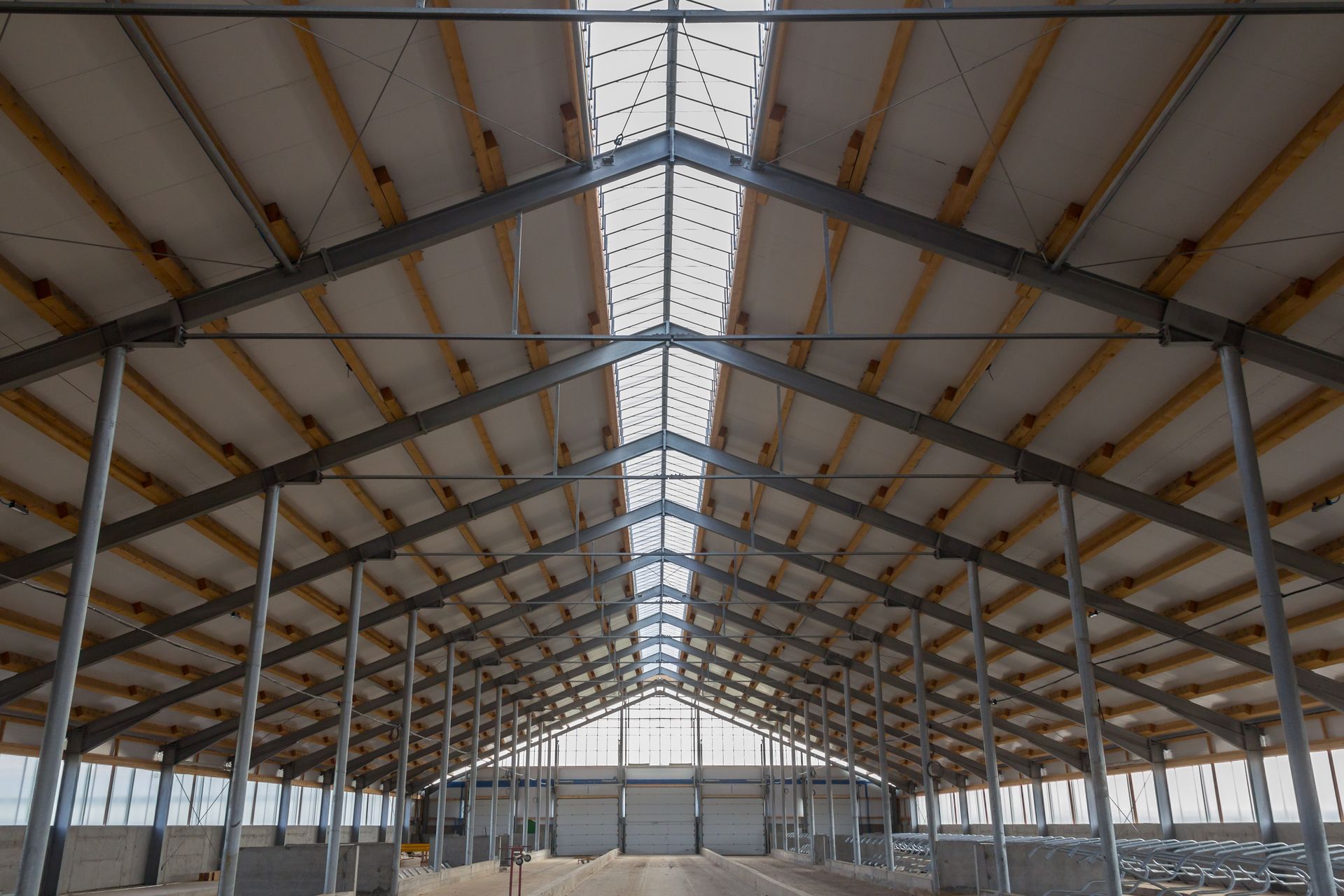 Interior of a large steel warehouse frame with a peaked roof and skylight strip, under construction