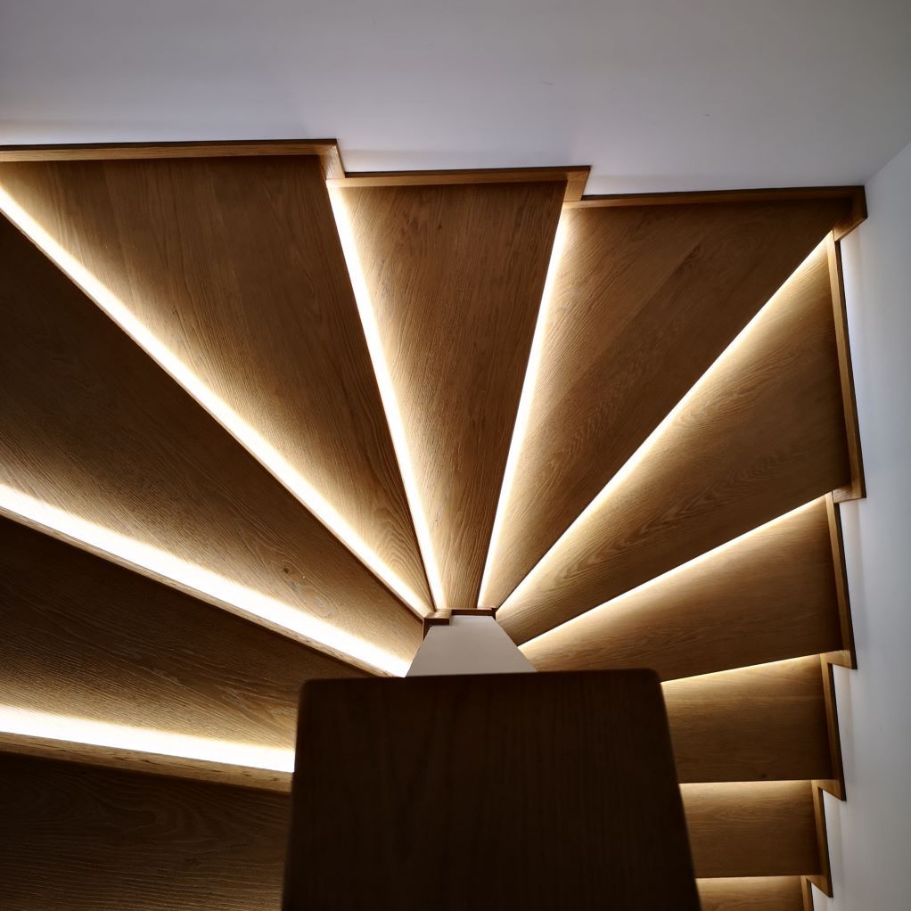 Un escalier en colimaçon en bois avec des lumières sur les marches