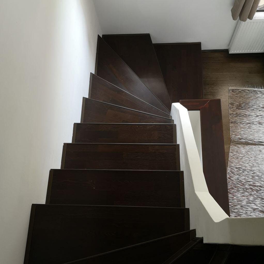 Un escalier en bois avec une rampe blanche menant au deuxième étage