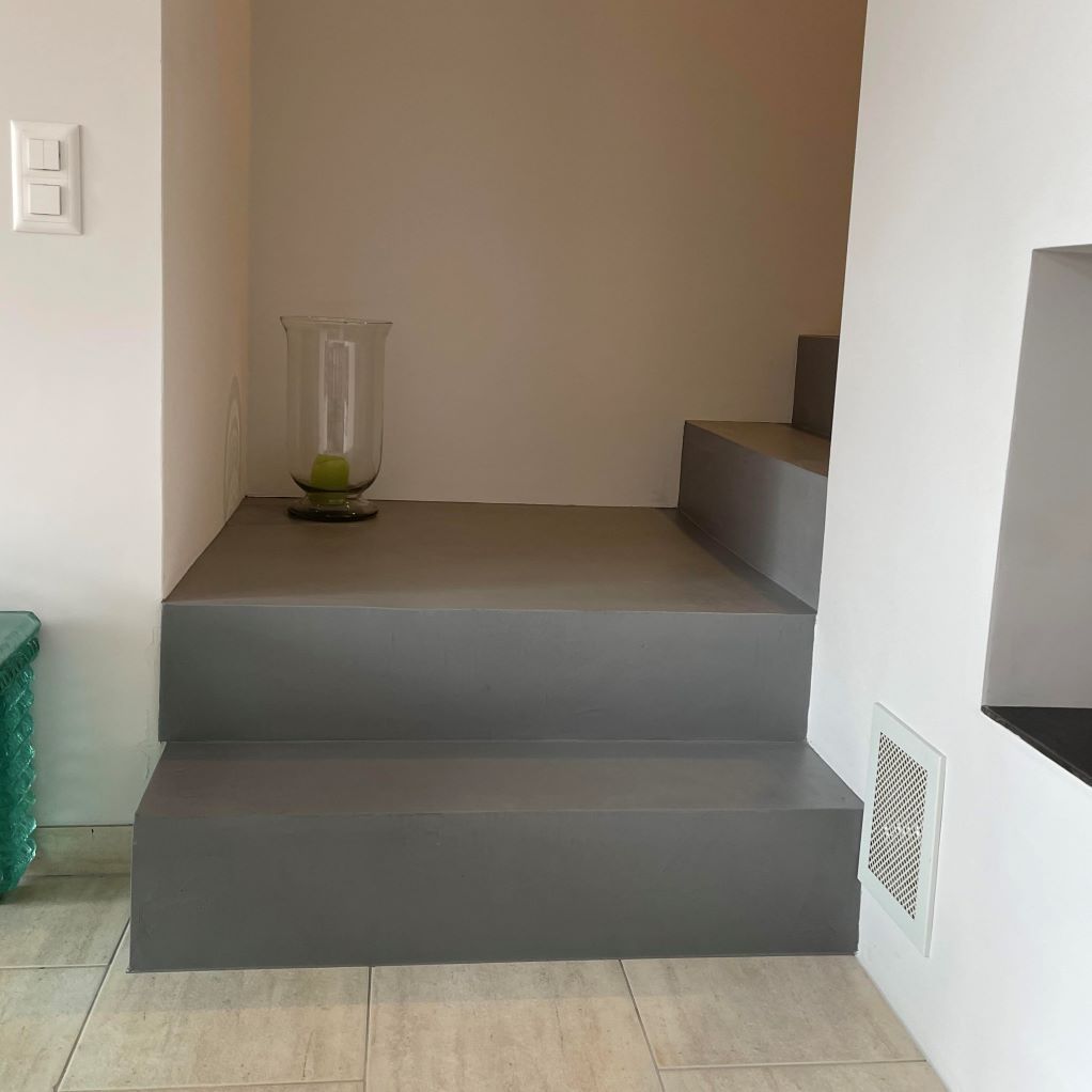 Un escalier gris avec un vase dessus