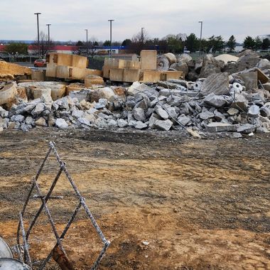 Construction site with concrete debris and a chain-link fence in the foreground.
