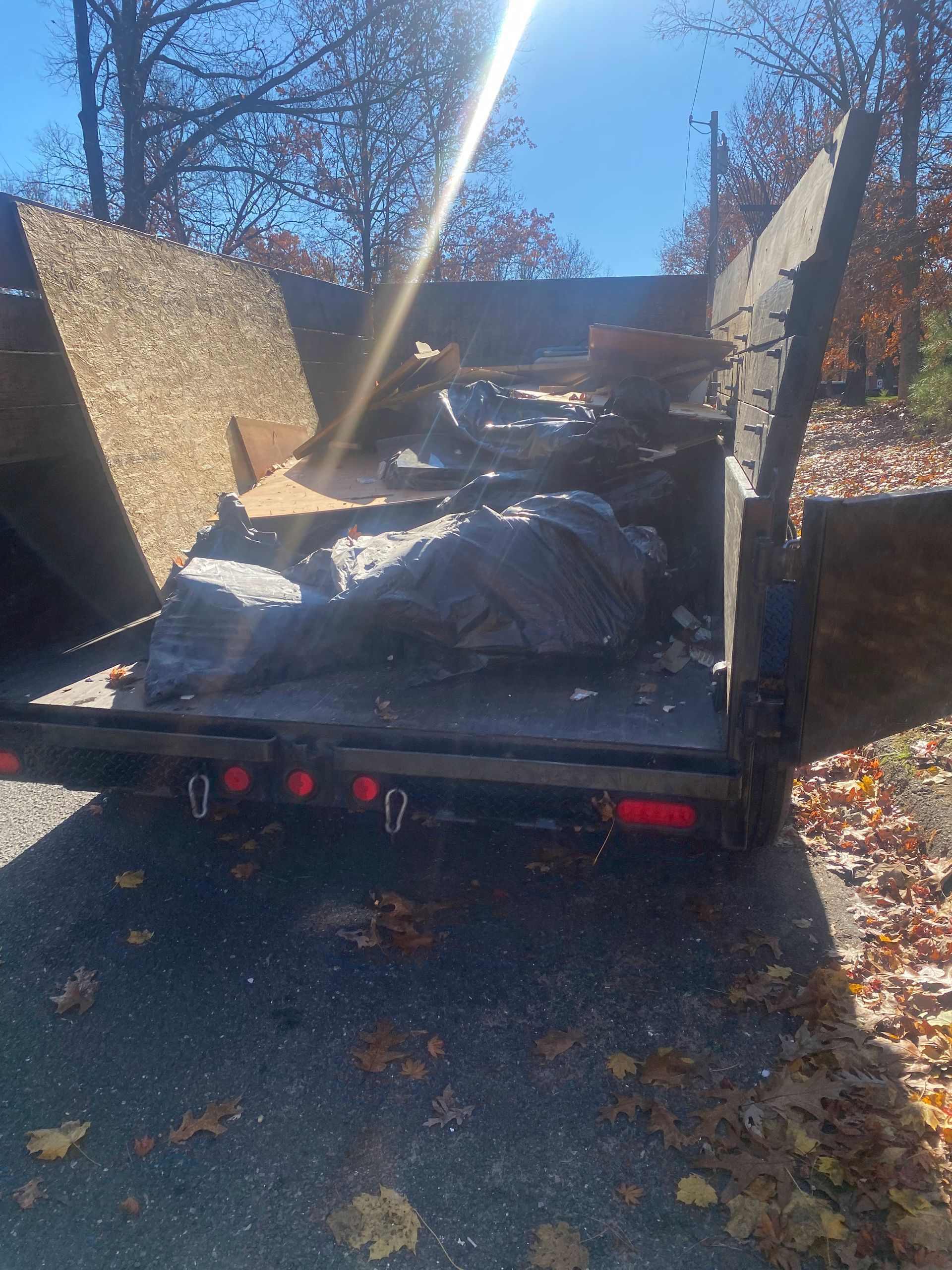 Dump trailer filled with debris and large rocks, outdoors on a sunny day