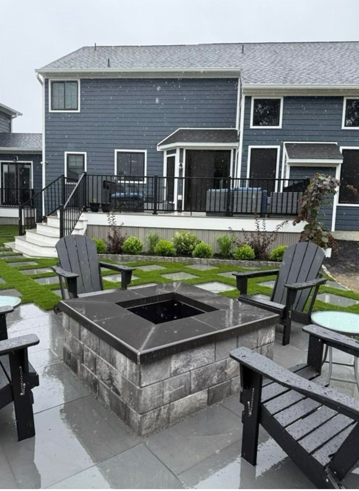 Backyard patio with fire pit, Adirondack chairs, and a raised deck behind a townhouse
