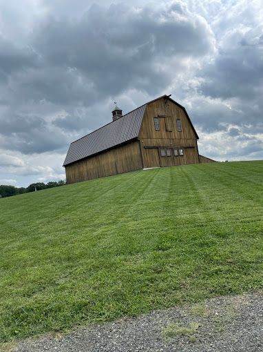Wooden barn on a grassy hill under a cloudy sky