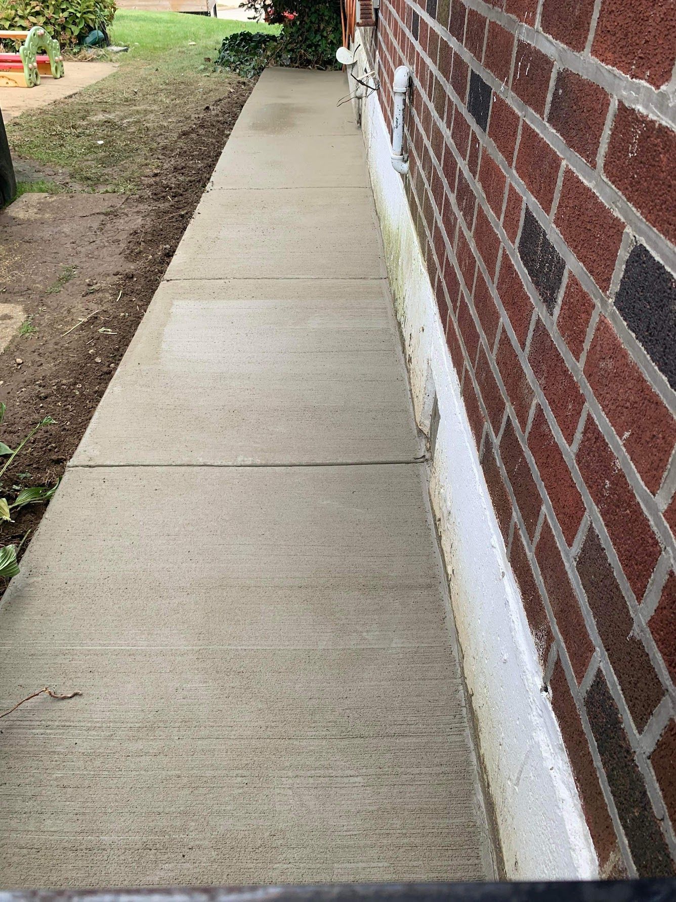 Concrete sidewalk next to a red brick wall
