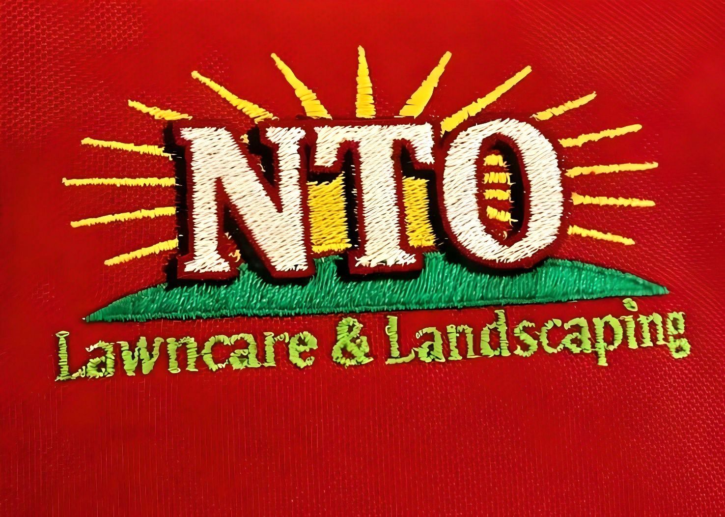 Embroidered logo for NTO Lawncrare & Landscaping on a red background. Features the letters NTO above green grass and the sun in yellow rays