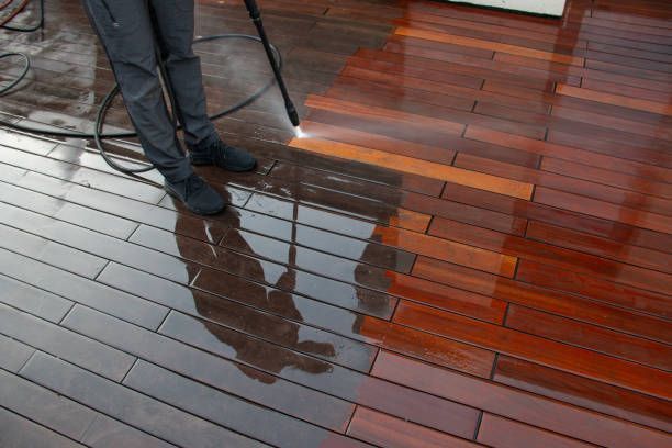 Nto lawn care & landscaping employee pressure washing a wooden deck, half clean, half dirty, dark wood in vineland, nj