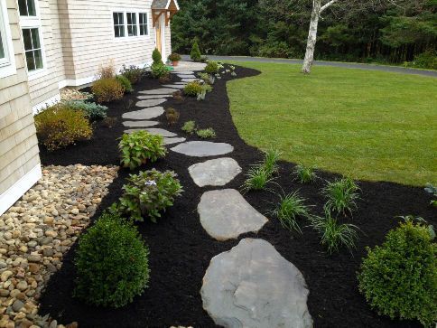 Stone pathway through garden beds with mulch and greenery