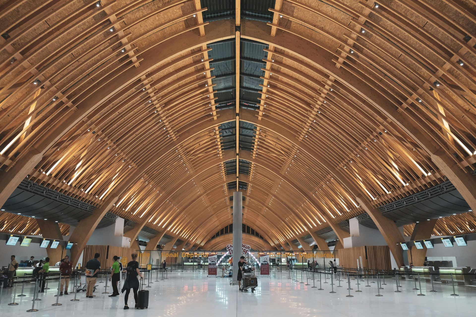 A large building with a wooden ceiling and people standing in it.