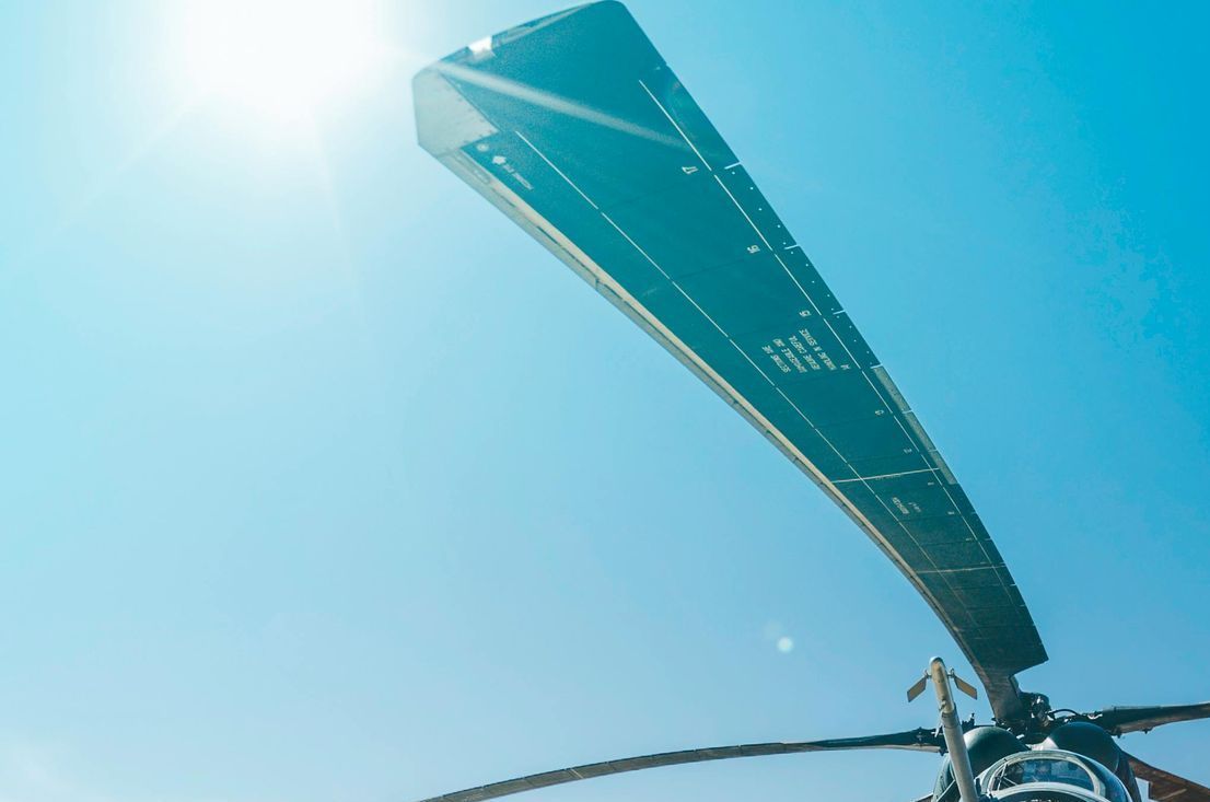 A close up of a helicopter propeller against a blue sky