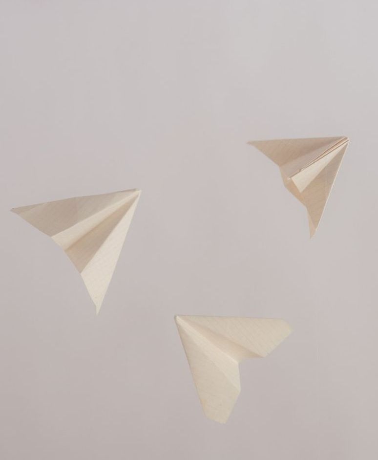 Three paper airplanes are flying in the air on a gray background.