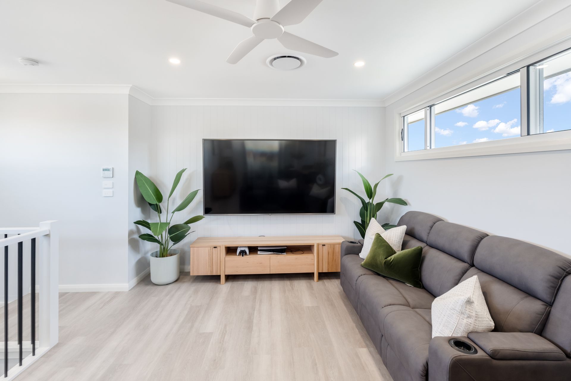 Bright Living Room With Gray Sofa, Large TV and White Walls and Ceiling Fan — Matt Made Building in Camden, NSW