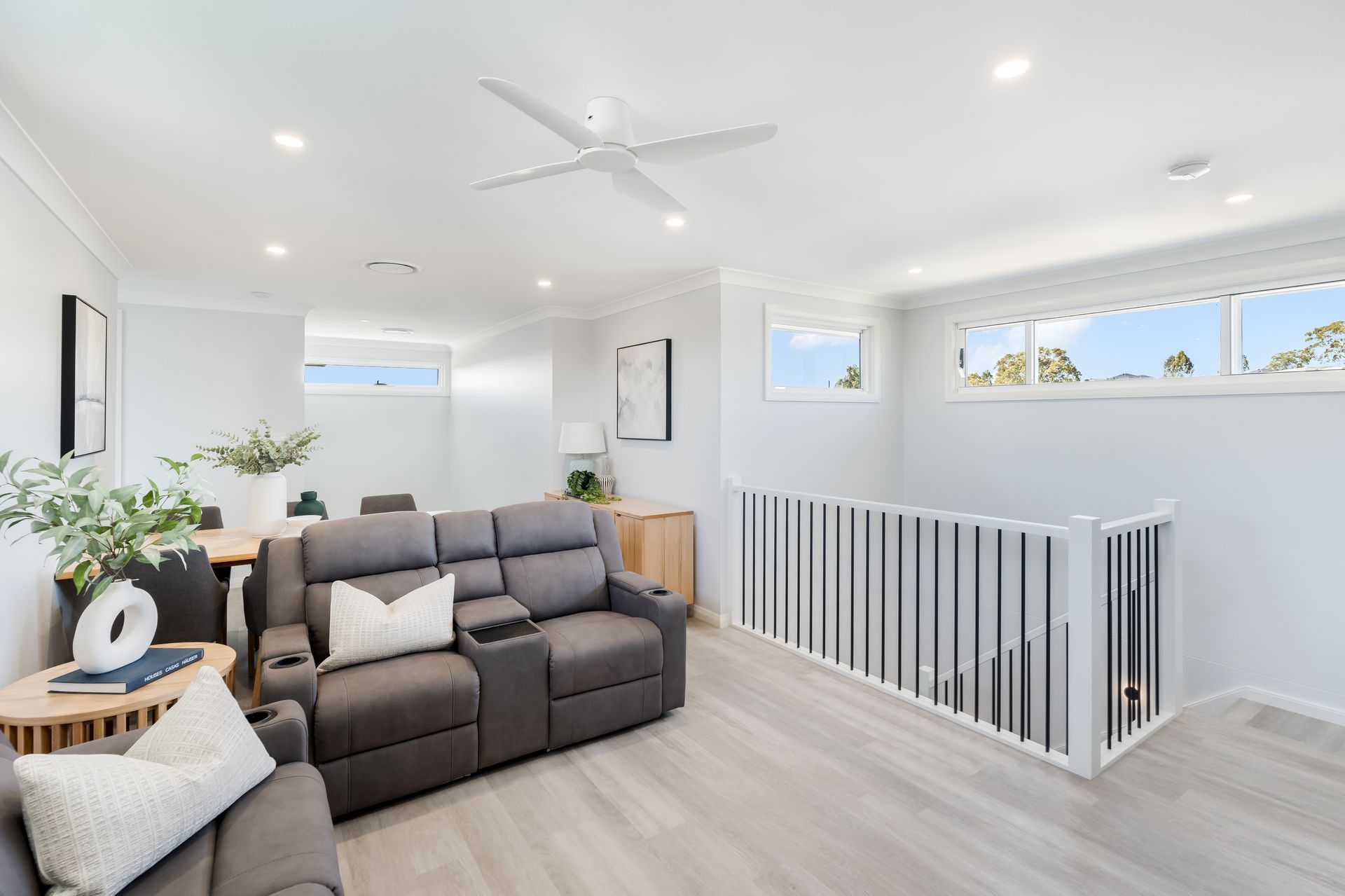 Bright Modern Living Room With Gray Sectional and Stair Railing by Large Windows — Matt Made Building in Camden, NSW