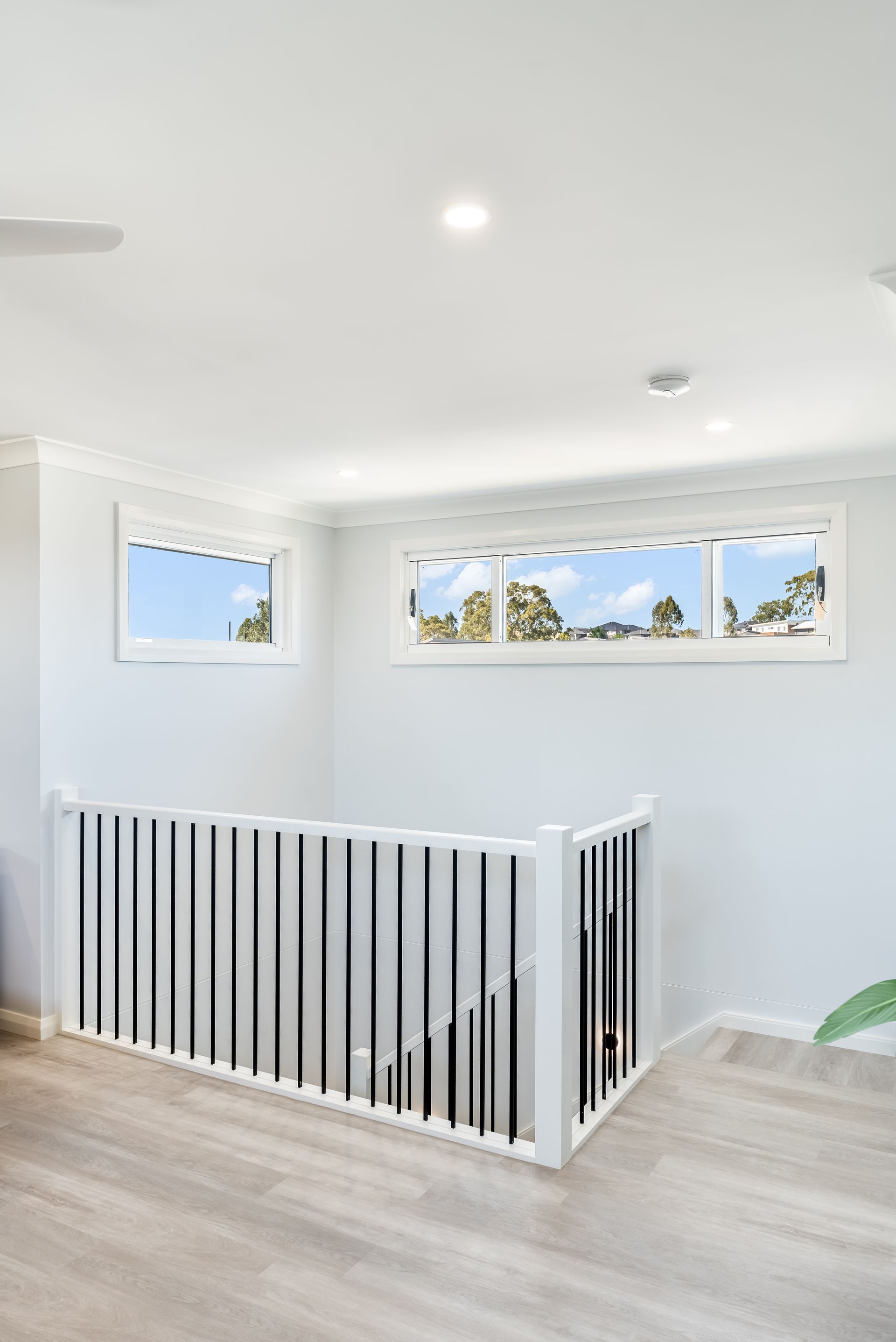 Bright White Hallway With a Black-and-white Stair Railing and Narrow Windows — Matt Made Building in Camden, NSW