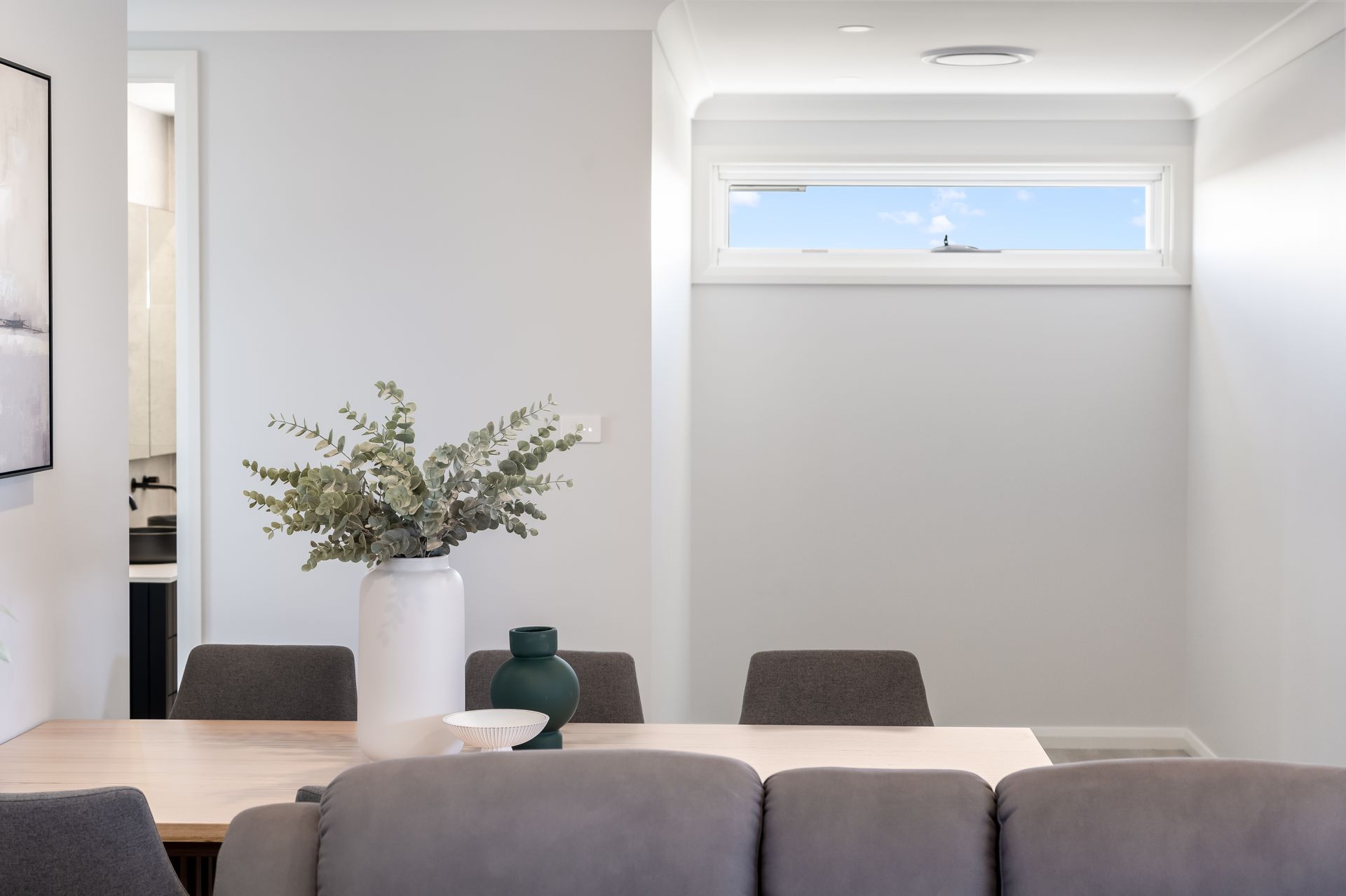 Minimal Dining Area With Gray Chairs, White Table and a Small High Window — Matt Made Building in Camden, NSW