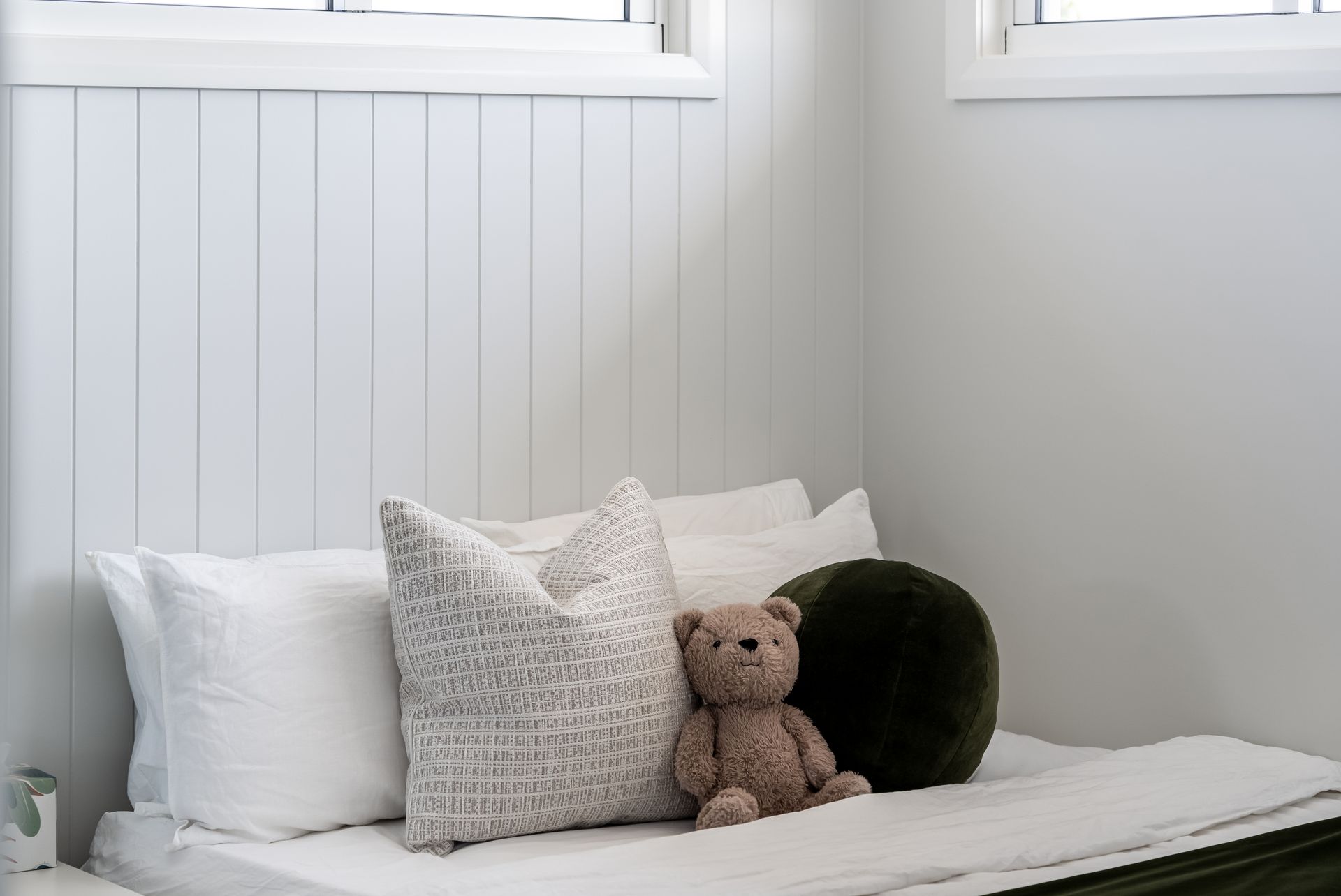 White Bed With Pillows and a Teddy Bear in a Bright, Minimalist Bedroom Corner — Matt Made Building in Camden, NSW