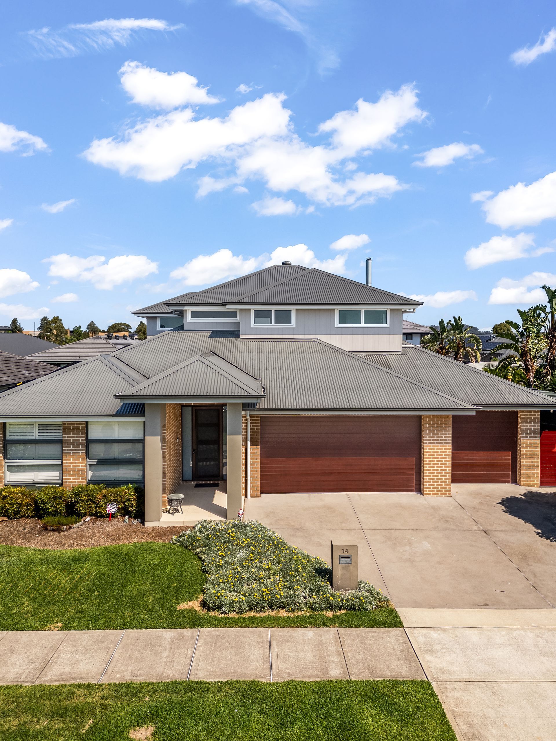Two-story Suburban House With a Tiled Roof, Red Garage Doors — Matt Made Building in Camden, NSW