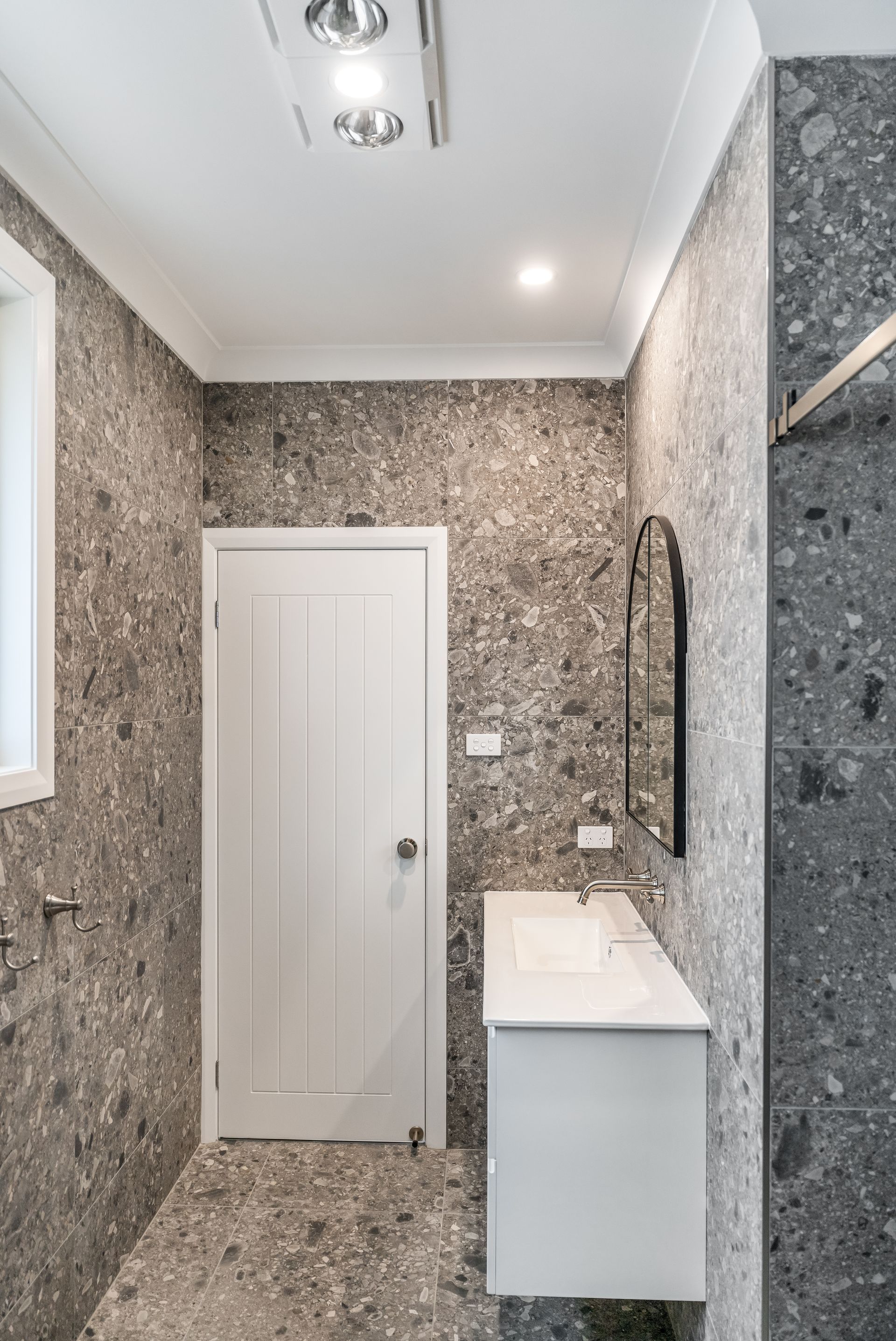 Narrow Tiled Bathroom With a White Vanity and Closed Door — Matt Made Building in Camden, NSW